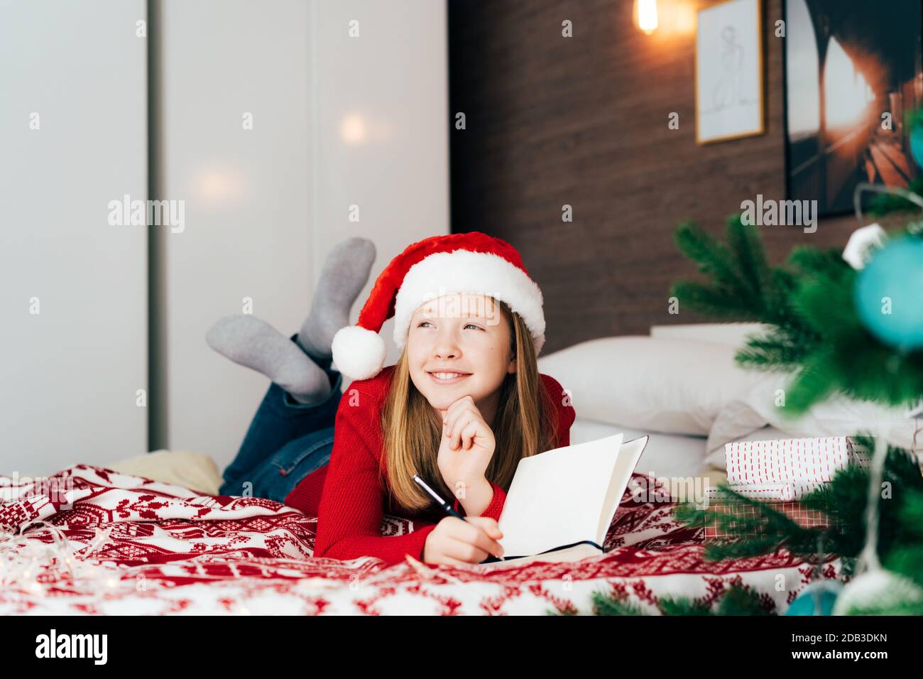 Rothaarige Teenager-Mädchen in einem weihnachtsmann Hut liegen auf die Bett Stockfoto