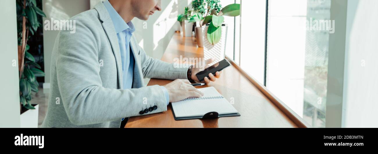 Online-Training ein Student schreibt den Text einer Vorlesung Von ihrem Telefon zu einem Notepad Stockfoto
