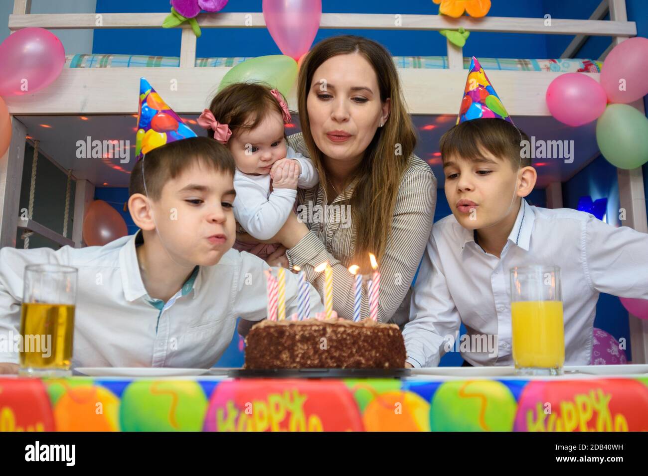 Familie bläst Kerzen auf Geburtstagskuchen Stockfoto