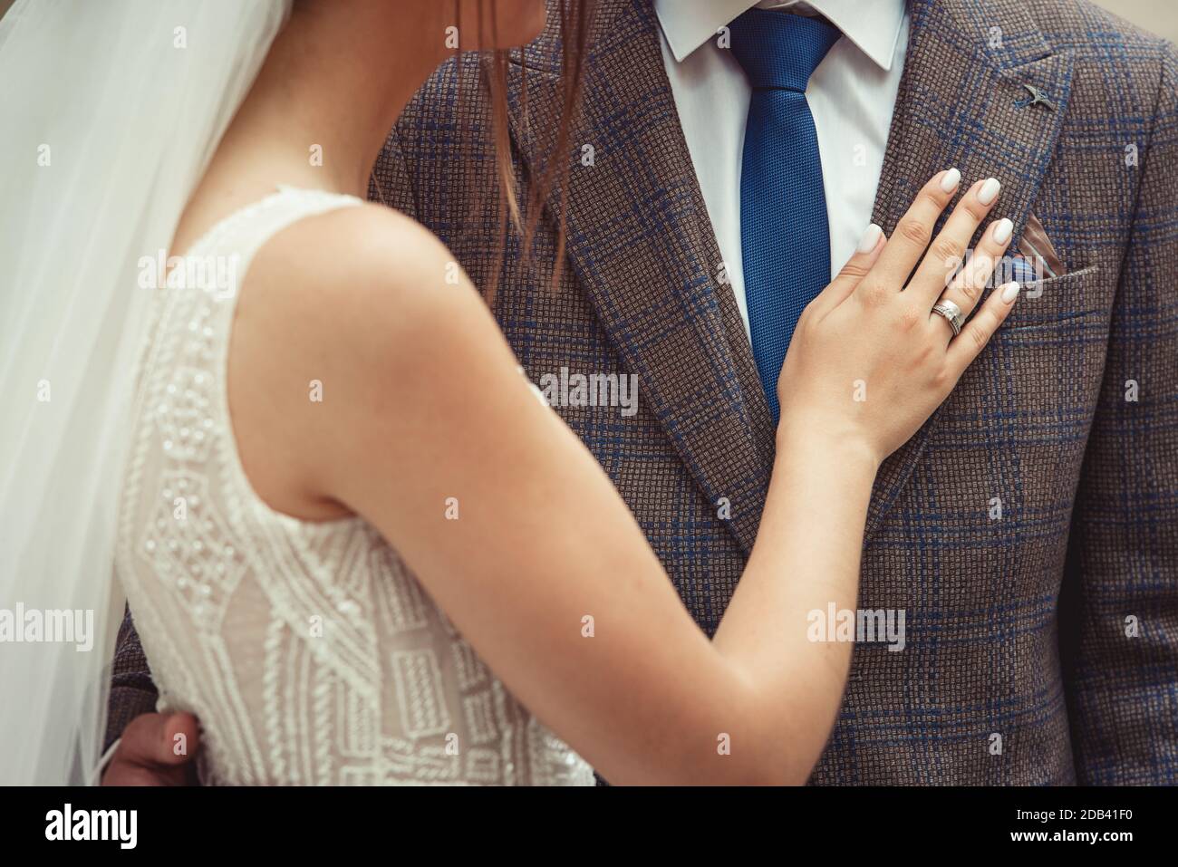 Braut und Bräutigam Hochzeitspaar mit Nahaufnahme auf der Hand der Frau auf der Brust des Mannes. Braun karierte Jacke Stockfoto