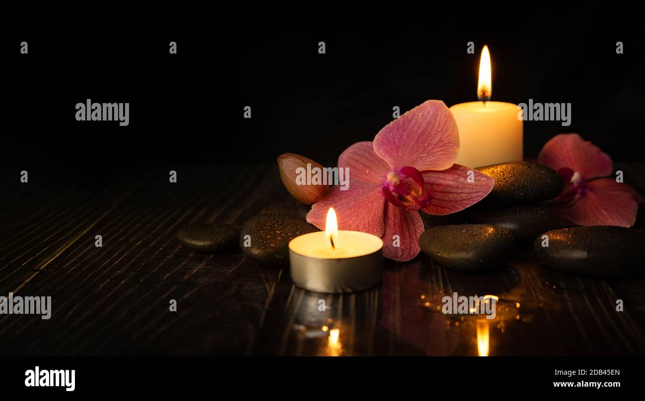 Orchideenblume mit Spa-Steinen und Kerzen. Meditation und Harmonie Konzept Stockfoto