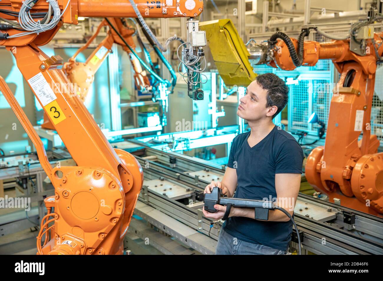 Techniker steuert mit Fernbedienung des Industrieroboters in der Fabrik. Automatisches Schweißen und Kleben mit Automatisierungs- und Roboterarmen. Stockfoto