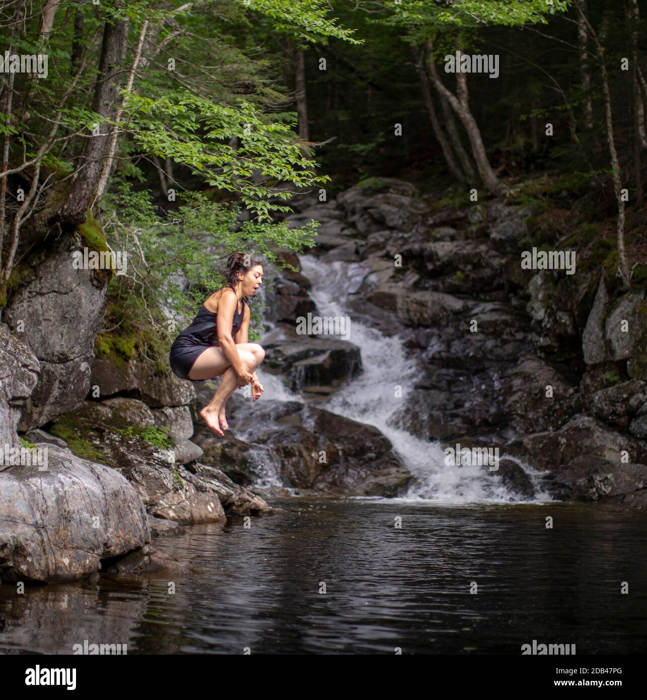 Frau, die in der Nähe von Thirteen Falls, White Mountains, New Hampshire, USA, ins Wasser springt Stockfoto