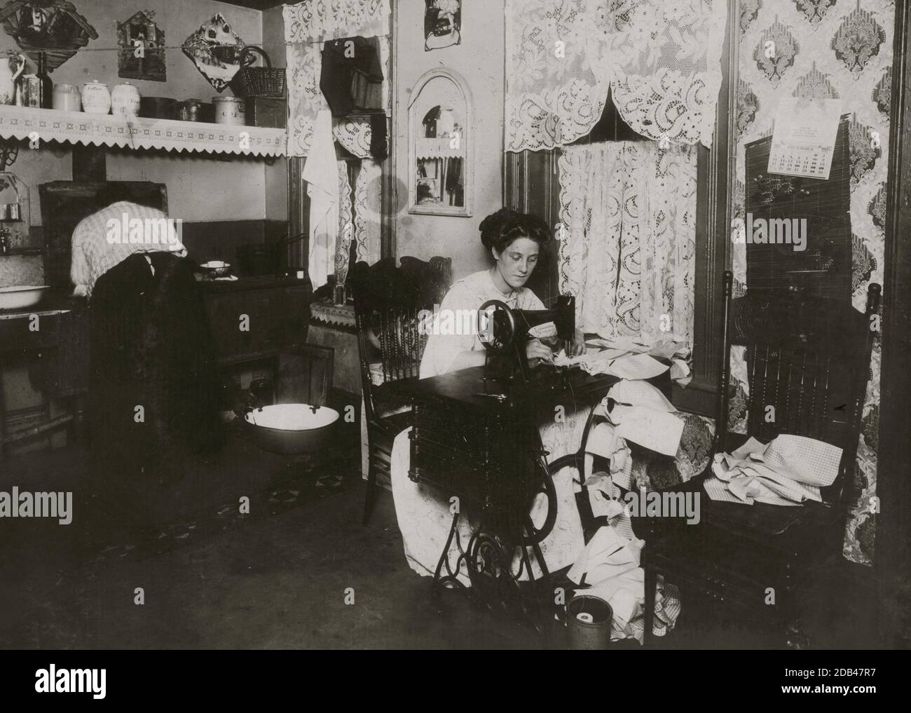 Annie Maier (oder Meyer), die Campbell-Kinderpinafores in ihrem Kellerhaus macht. 71 E. 108 Street. Es wurde berichtet, dass sie an Tuberkulose erkrankt war. Arbeiten in der Küche. Stockfoto