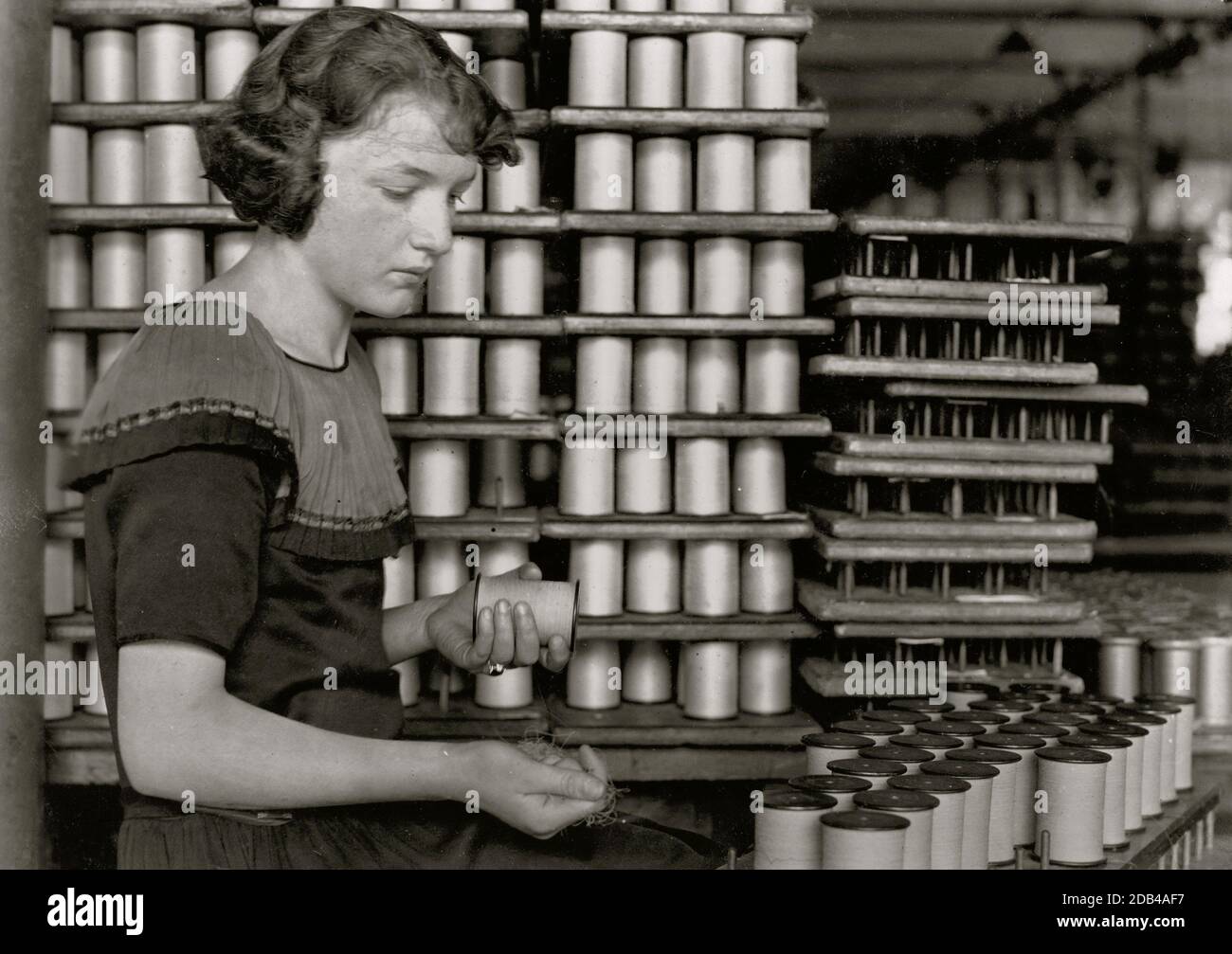 Young Girl stapelt Spulen aus Seidenfaden. Stockfoto