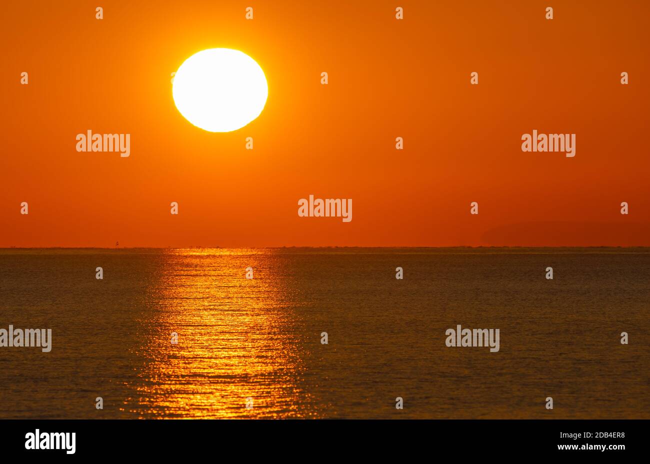 Landschaftsansicht des niedrigen Sonnenuntergangs, zeigt Sonnenuntergang über dem Meer mit einer klaren Reflexion im Wasser. Stockfoto