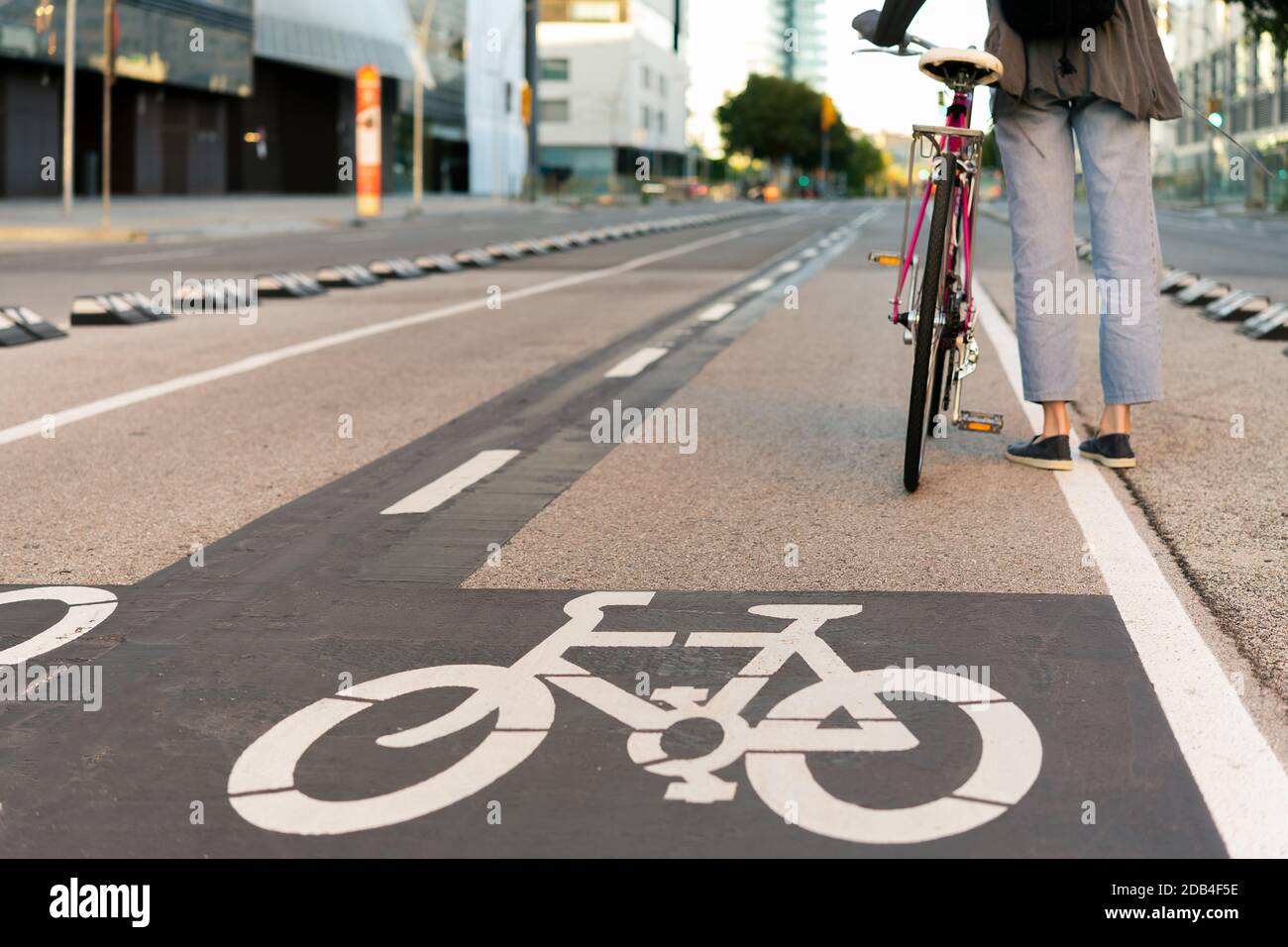 Rückansicht der Beine einer unerkennbaren jungen Frau, die am Radweg mit einem pinken Fahrrad im Retro-Stil steht, Konzept des aktiven Lebensstils und der Lust Stockfoto