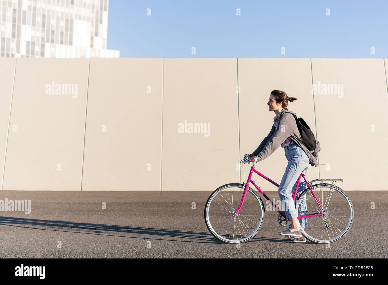 Glückliche junge Frau auf einem rosa Retro-Fahrrad, Konzept des aktiven Lebensstils und nachhaltige urbane Mobilität Stockfoto