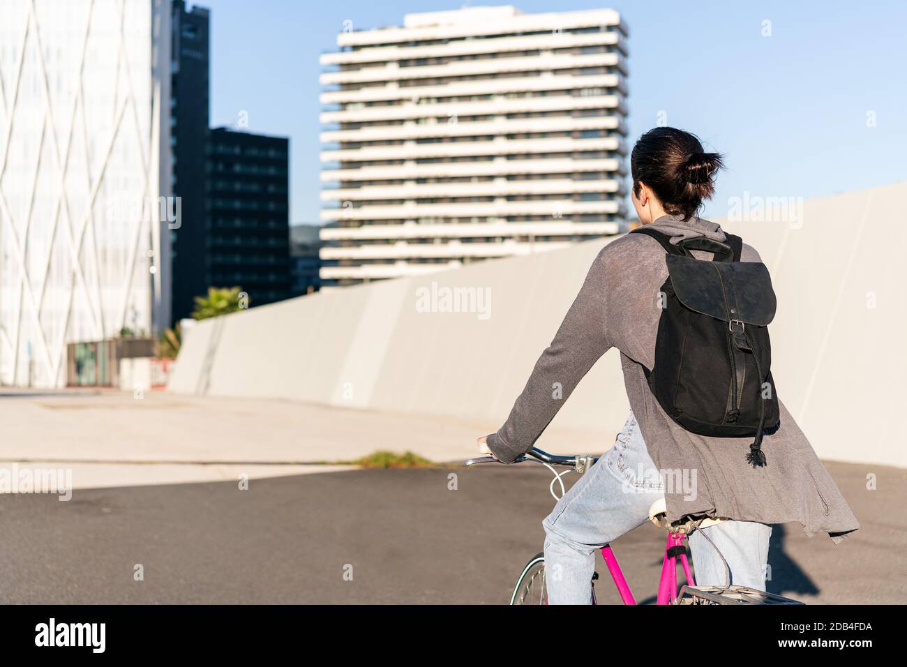 Rückansicht eines unerkennbaren jungen Mädchens mit Rucksack auf einem rosa Retro-Bike, Konzept des aktiven Lebensstils und nachhaltiger urbaner Mobilität Stockfoto