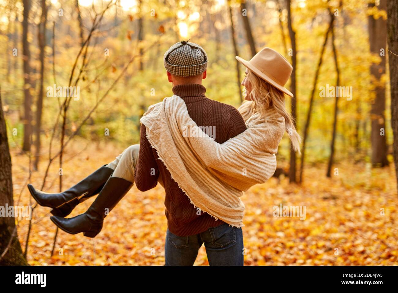 Rückansicht auf freundlichen Mann hält Freundin in den Händen, im Wald, an sonnigen Herbsttag. Liebesgeschichte Stockfoto