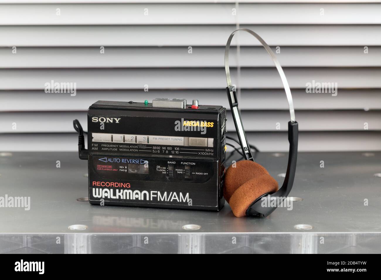 Klassischer Walkman ® Kassettenspieler und Stereokopfhörer auf einem Metalltisch, der in einem Musik- und Unterhaltungskonzept aufrecht in der Nähe steht Stockfoto