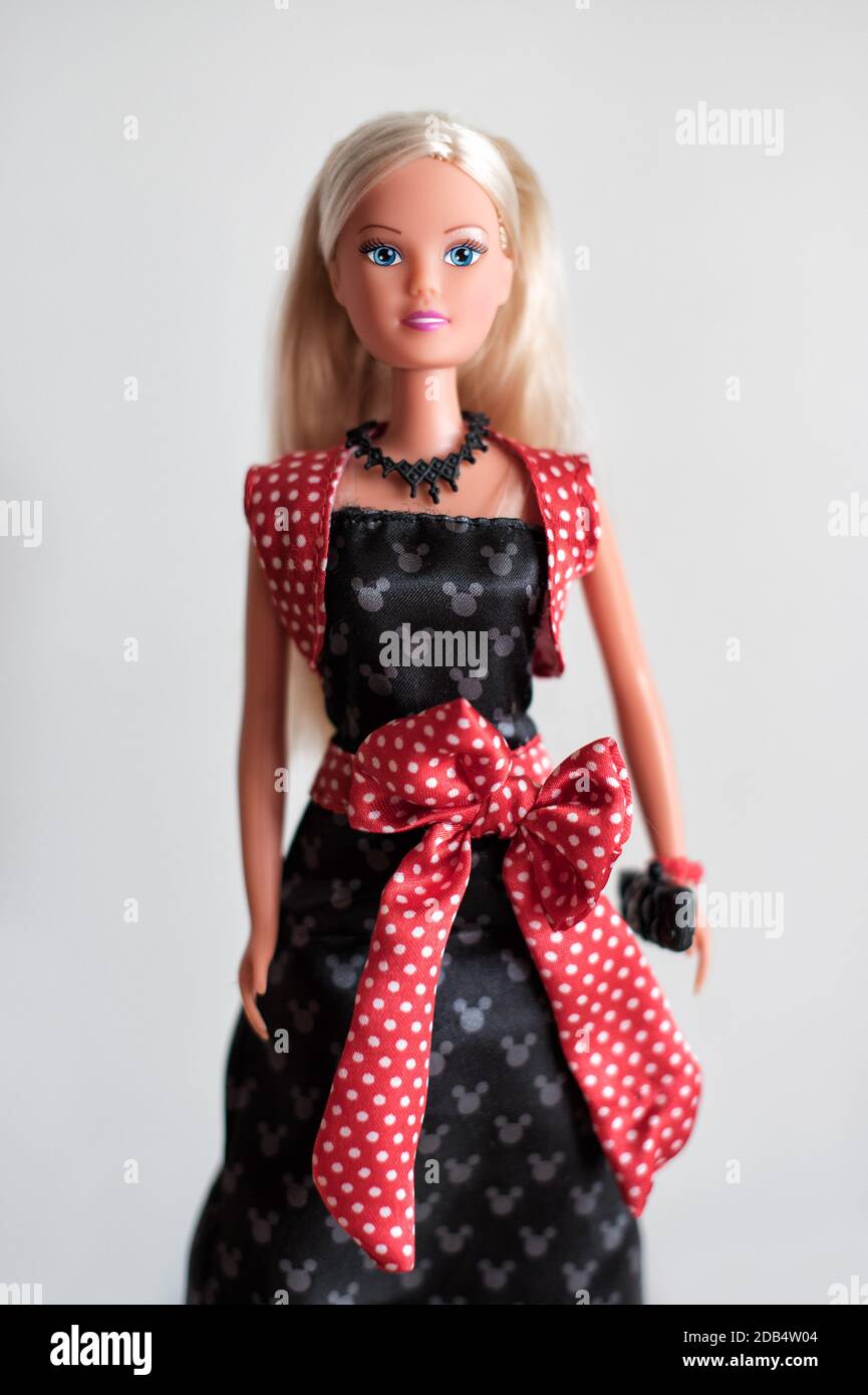 Barbie-Puppe mit langen blonden Haaren am Abend tragen mit Eine rote Schärpe, die einen Geldbeutel trägt, der auf grau isoliert ist Stockfoto