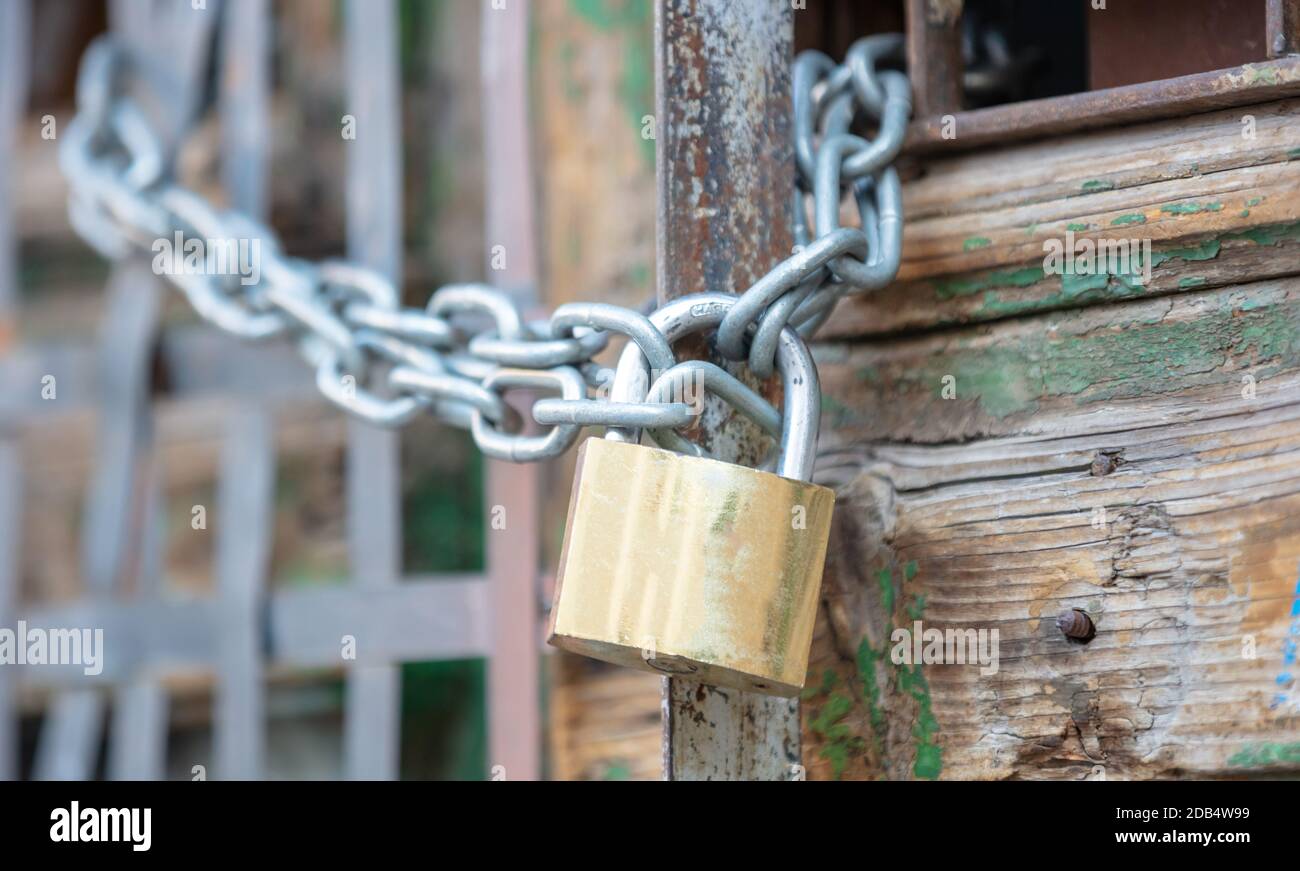 Schweres Metallvorhängeschloss mit Kette in der Nähe eines Eingangstors. Sicherheit, Sicherheitskonzept Stockfoto