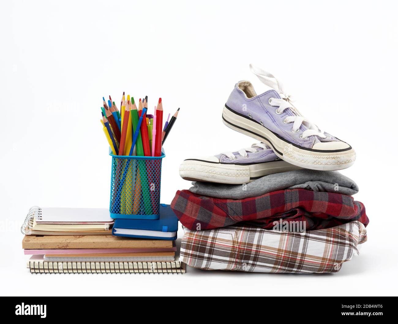 Stapel gefalteter Kleidung, Sport-Sneaker, Briefpapier auf weißem Hintergrund, Konzept zur Hilfe für Bedürftige, Spende Stockfoto