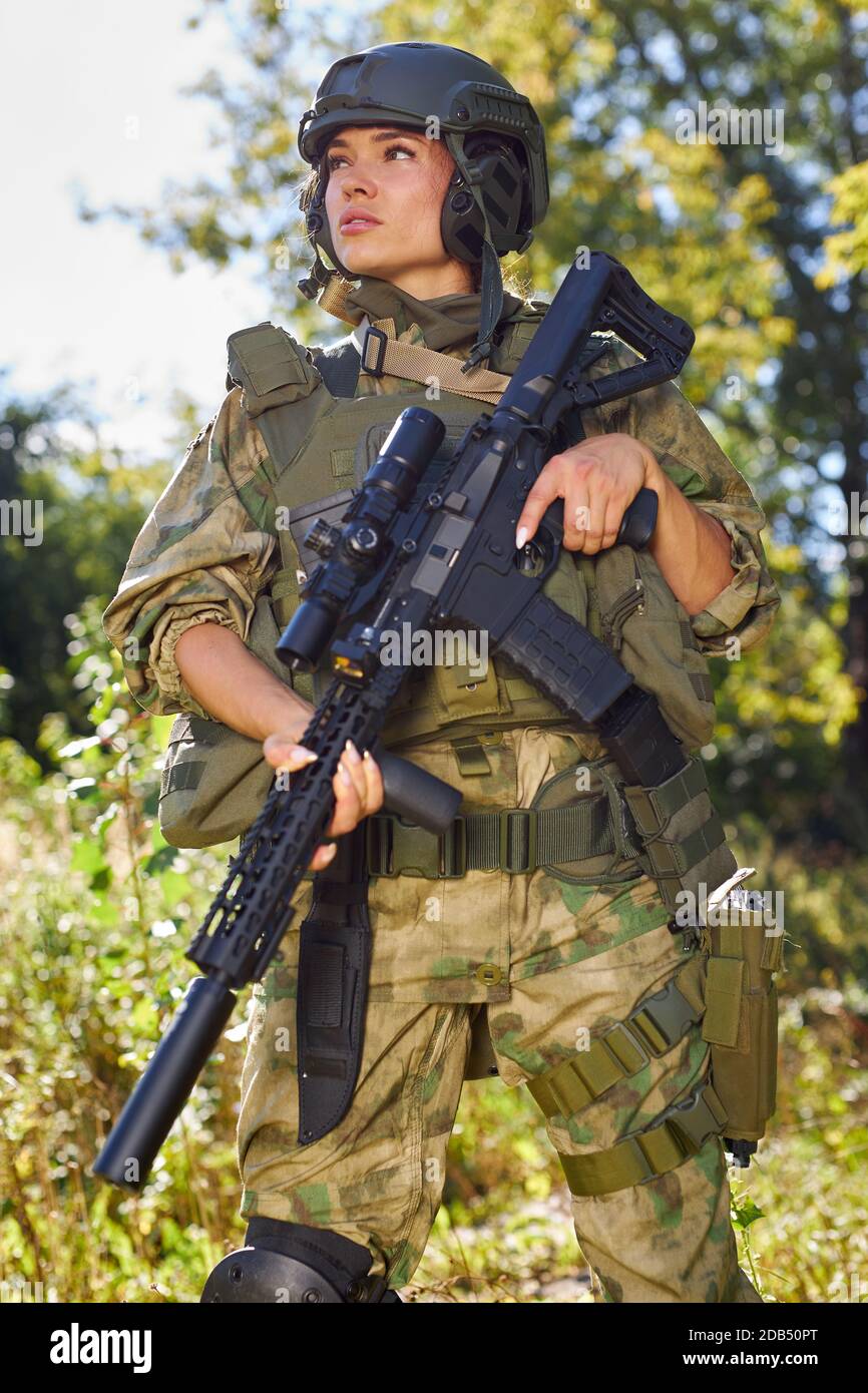 Junge kaukasische Militärfrau hält eine Waffe in der Hand in der Natur, sie wird jagen, Jagd im Wald ist ein Hobby. Spiel mit Waffen Stockfoto
