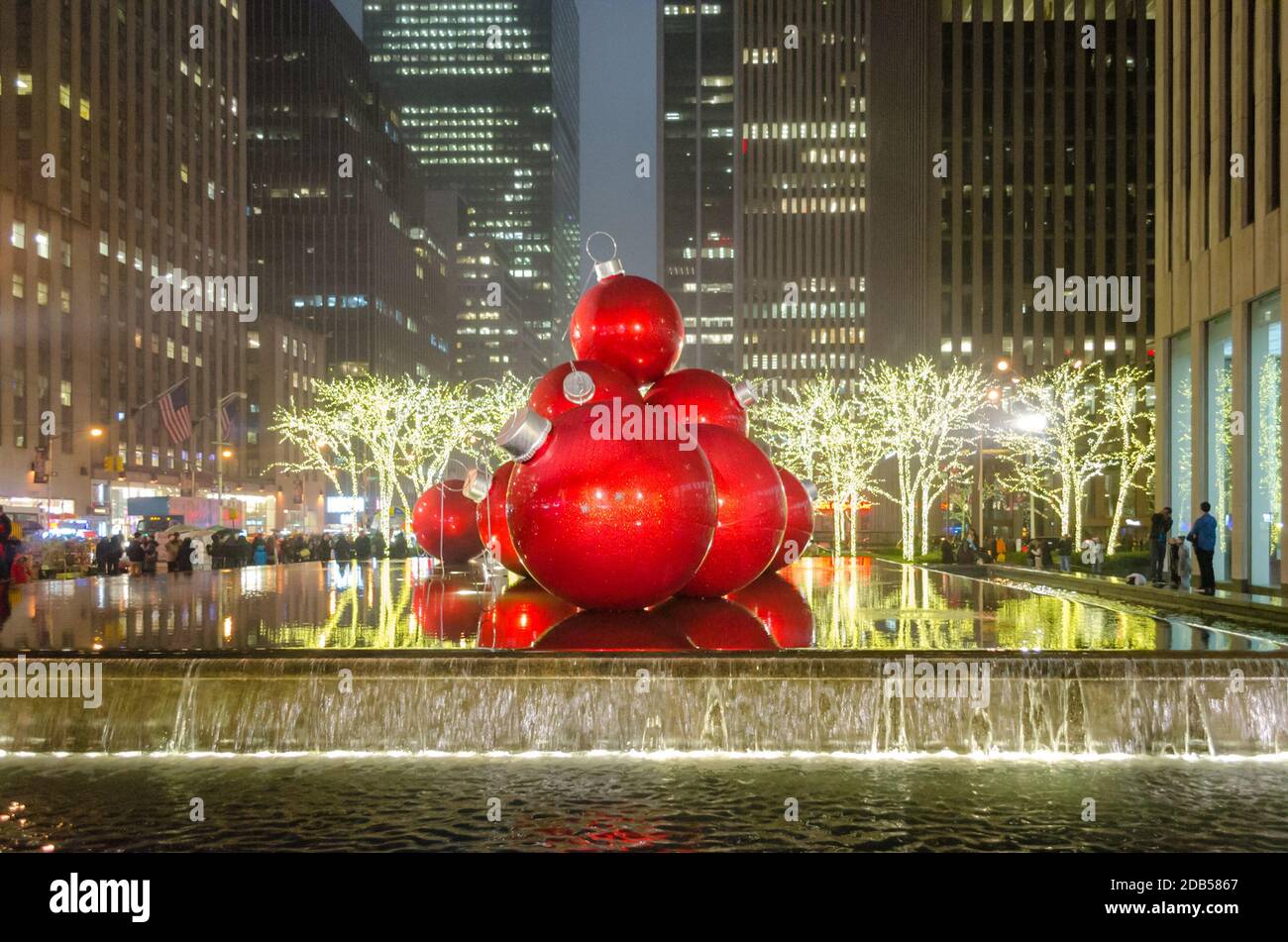 Riesige Weihnachtsschmuck auf einem Brunnen in Manhattan bei Nacht. Große Bälle und helle Lichter Dekoration in 6th Avenue. Wolkenkratzer im Hintergrund. Stockfoto