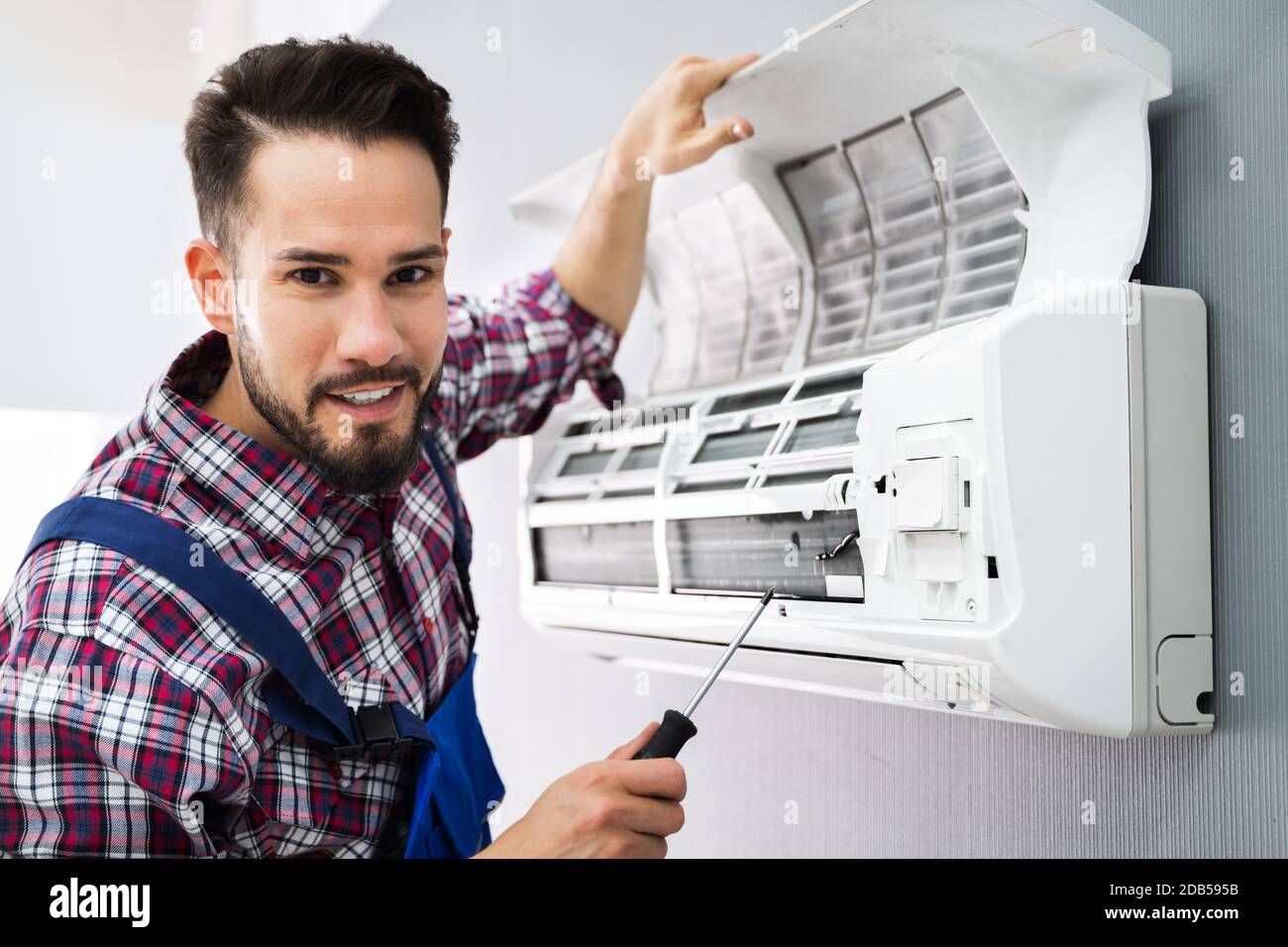 Happy männlichen Techniker Reparatur Klimaanlage mit Schraubendreher Stockfoto