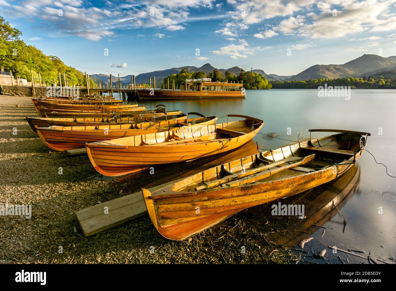 Hölzerne Ruderboote aufgereiht am Ufer mit goldenem Licht von der untergehenden Sonne beleuchtet. Derwentwater, Lake District, Großbritannien. Stockfoto