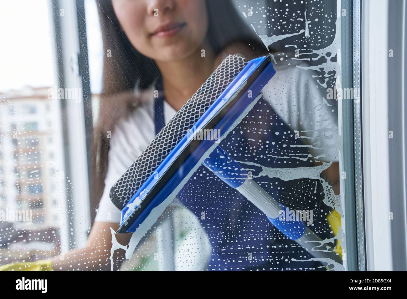 Lassen Sie das Fenster leuchten. Nahaufnahme einer jungen Frau, die das Fenster mit dem Rakel putzte. Hausarbeit und Housekeeping, Reinigungsdienstkonzept Stockfoto