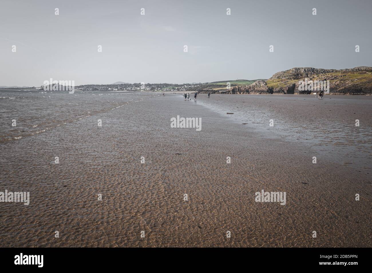 Menschen, die am Strand von Black Rock Sands in Nordwales, Großbritannien, spazieren gehen Stockfoto