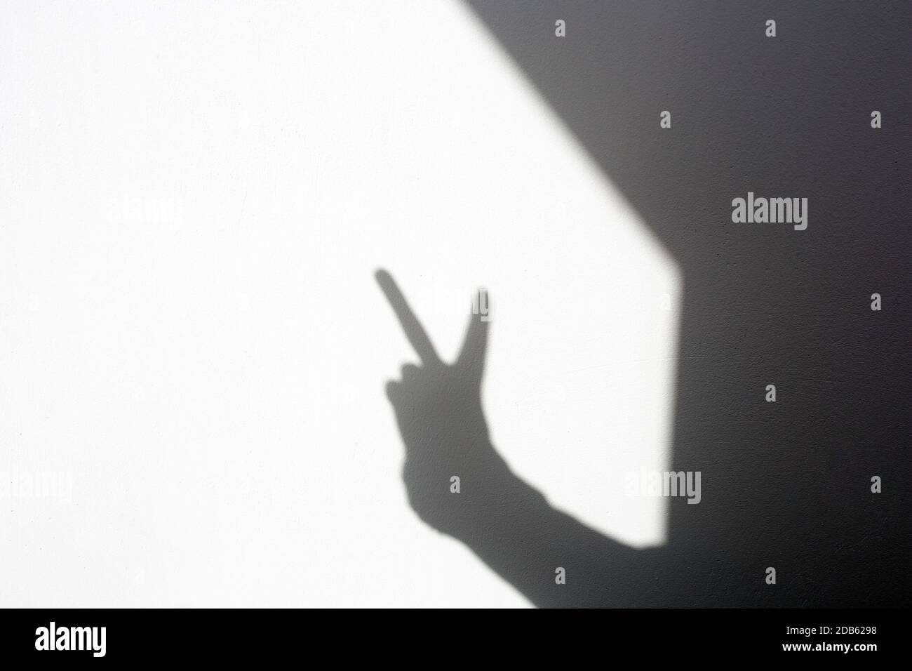 Silhouette Schattenhand mit einem Friedenszeichen an der weißen Wand, isolierter Raum für Text Stockfoto