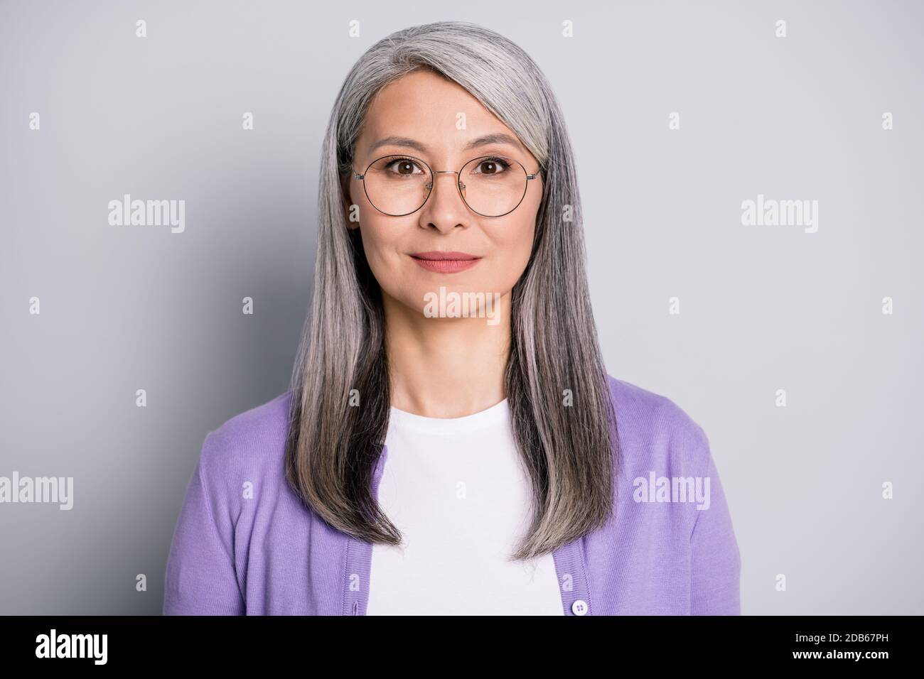 Portrait Foto von zuversichtlich ruhigen alten Frau trägt Brillen und Lila Strickjacke isoliert auf grauem Hintergrund Stockfoto