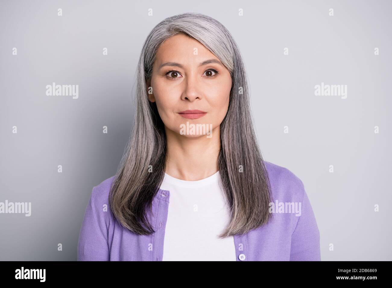 Portraitfoto einer ruhigen alten Dame mit langem Weiß Haare tragen lila  Strickjacke isoliert auf grauem Hintergrund Stockfotografie - Alamy