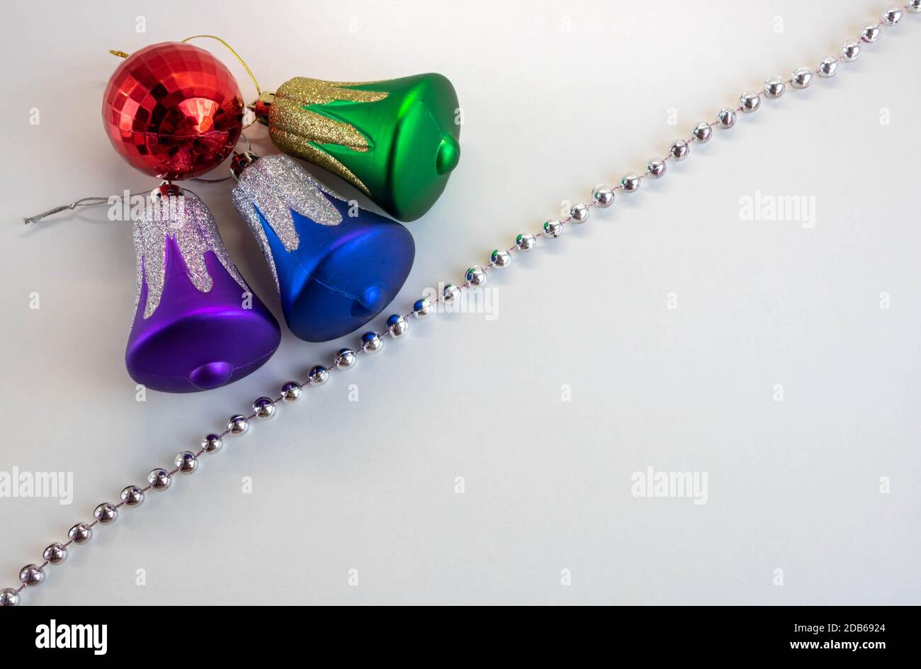 Dekorative Glocken, rote Kugel, silberne Perlen auf weißem Hintergrund. Weihnachtskomposition. Stockfoto
