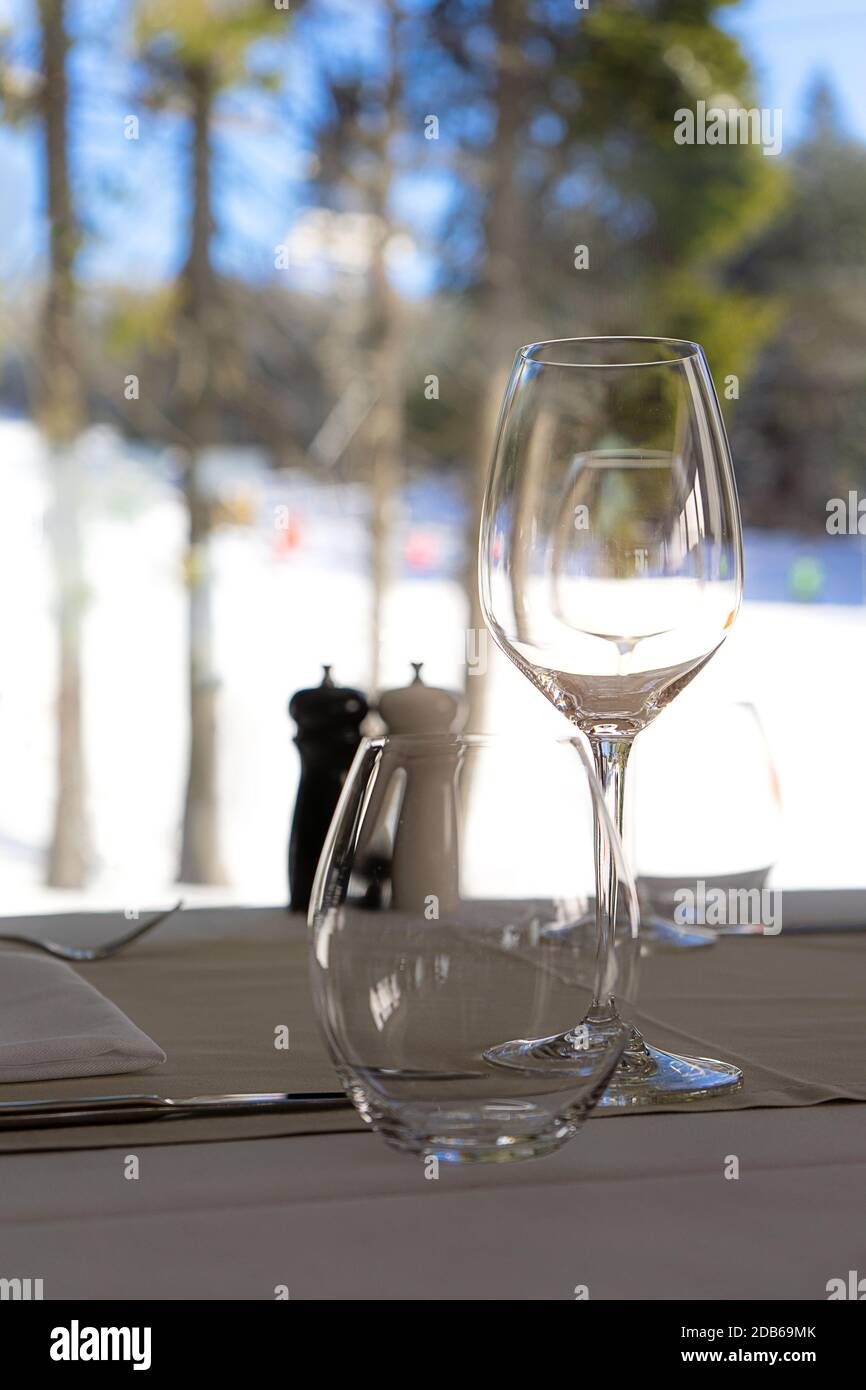 Blick vom Restaurant mit Gläsern Wein auf die verschneiten Pisten. Winterurlaub Konzept. Vorderansicht. Stockfoto