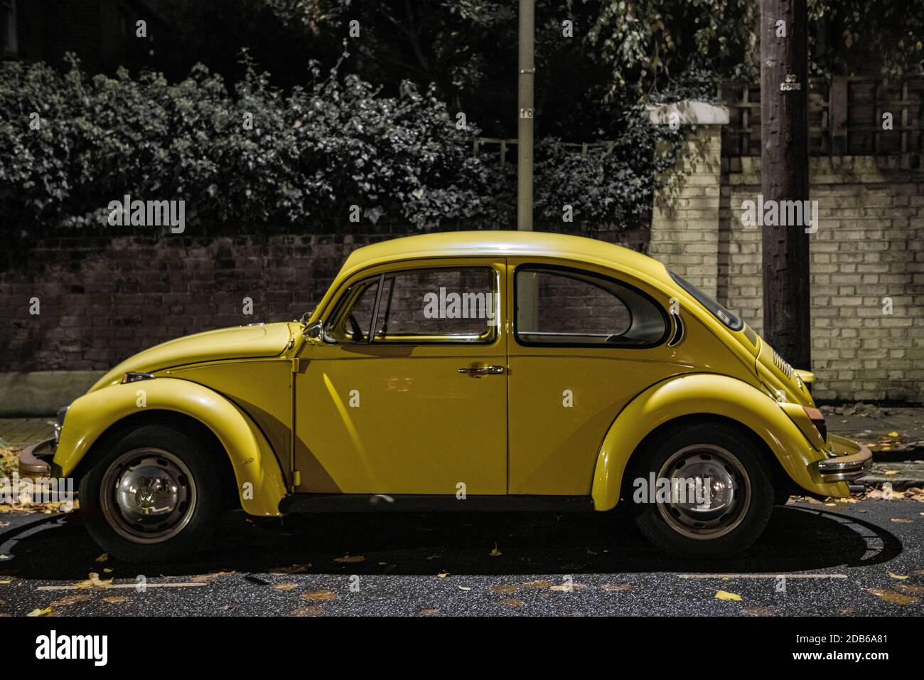 Ein schöner gelber VW Käfer parkte an einer Straße Nacht Stockfoto