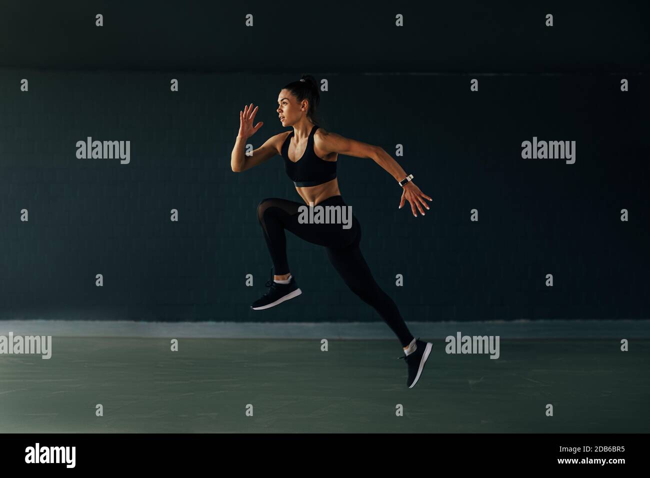 Sportlerin springt im Fitnessstudio und wärmt die Beine vor dem Training auf Stockfoto