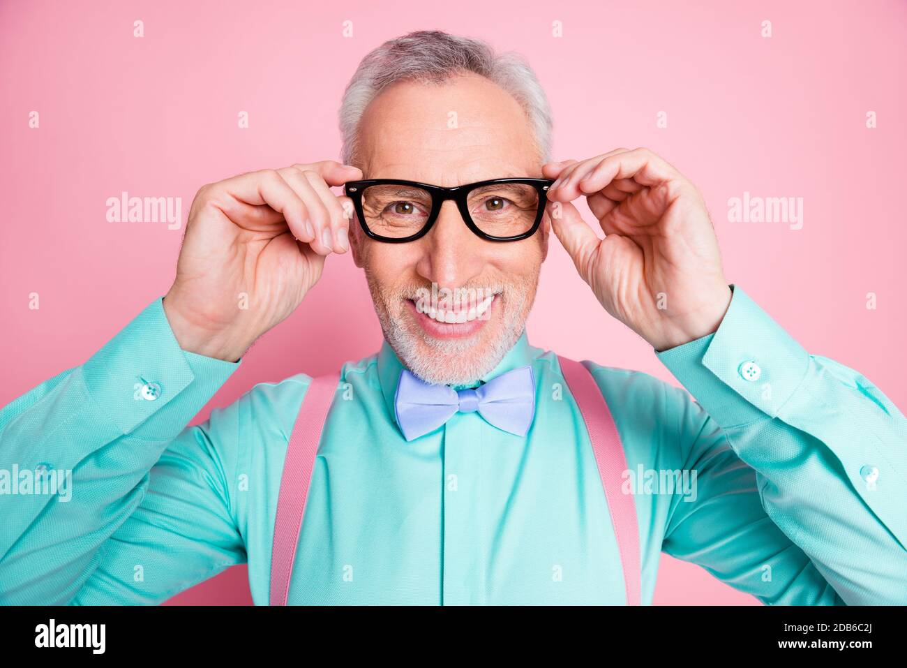 Nahaufnahme Kopfschuss Foto von Mann tragen Brillen Bowtie Hosenträger hell shirt lächelnd isoliert auf rosa Hintergrund Stockfoto