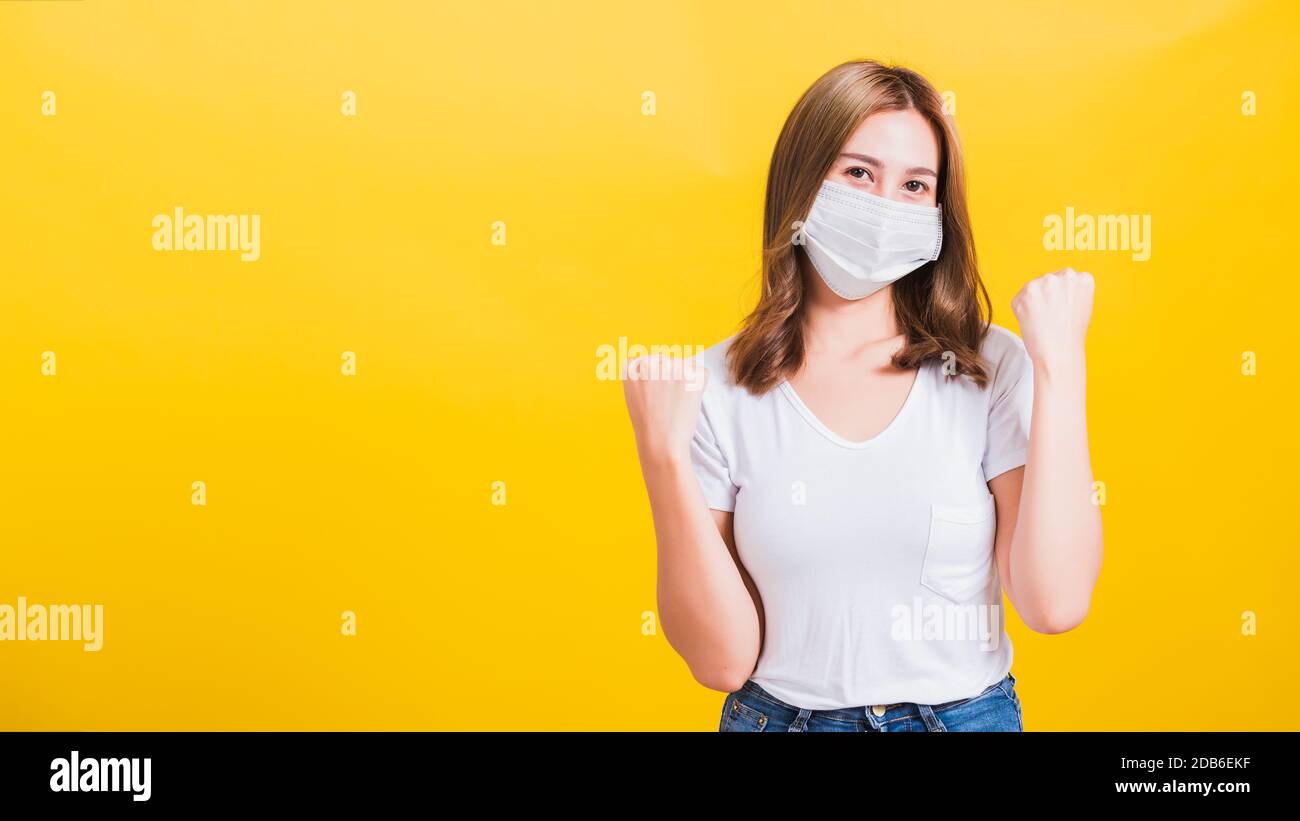 Asiatische schöne fröhliche junge Frau mit Gesichtsmasken-Schutz Filterstaub pm2,5, COVID-Virus und Luftverschmutzung ihre Hände froh fröhlich aufgeregt fröhlich heben Stockfoto