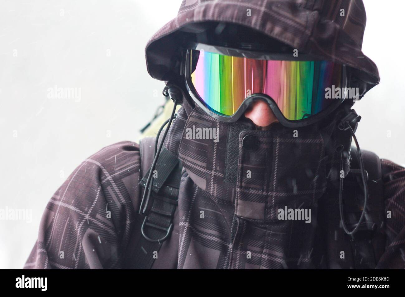 Porträt eines Touristen mit Rucksack bei schlechtem Wetter in den Bergen. Starker Schneesturm. Gesicht mit einer winddichten Maske geschlossen. Extreme Kleidung. Nahaufnahme Stockfoto