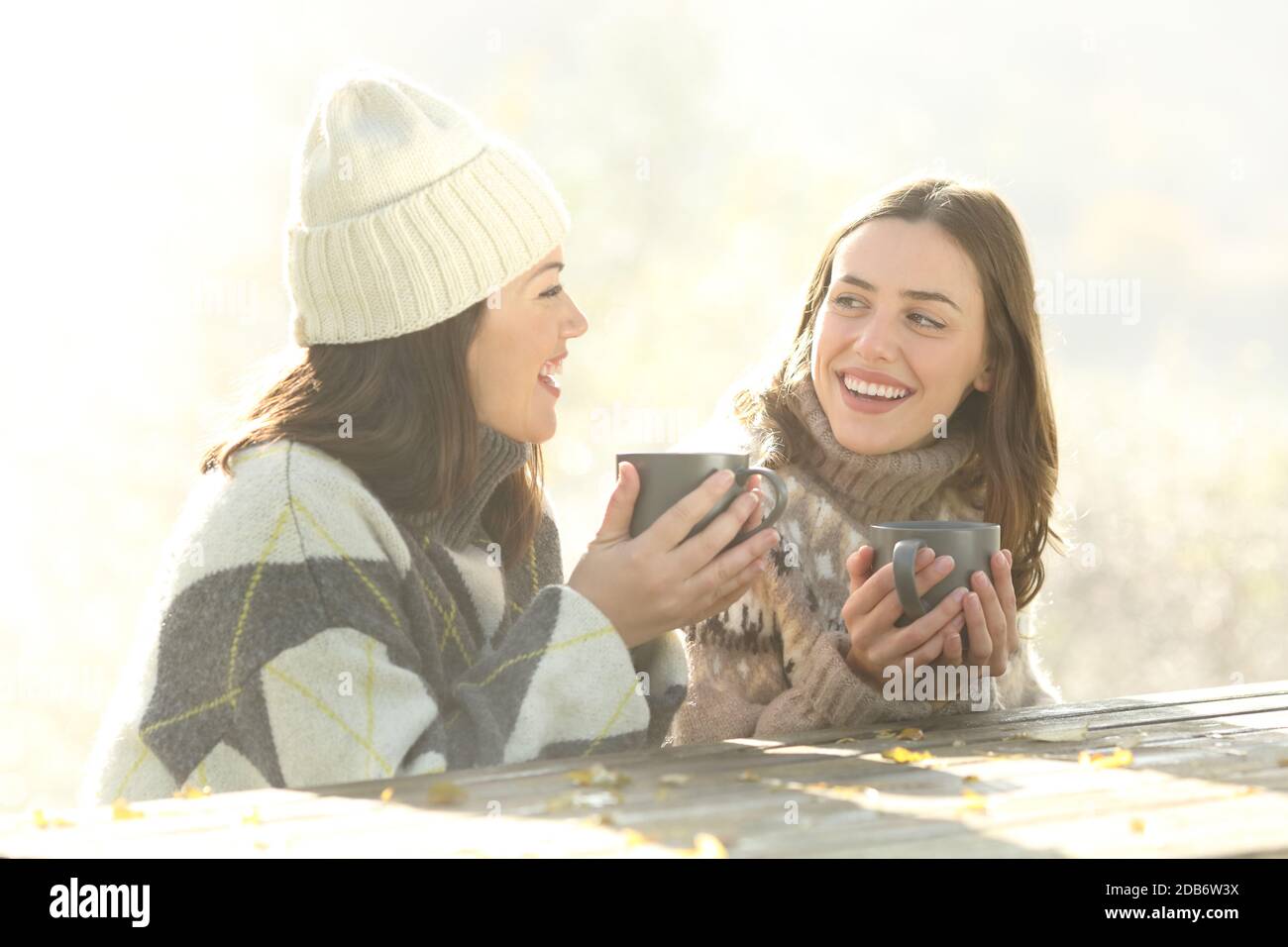 Zwei glückliche Freunde beim Frühstück sitzen im Winter neblig reden Morgens im Freien Stockfoto