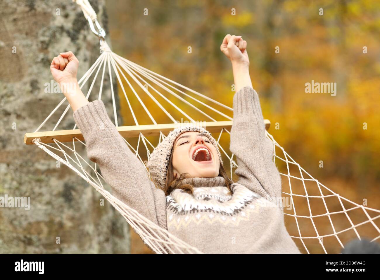 Aufgeregt Frau feiert Urlaub Anheben der Arme liegen in der Hängematte Herbst im Wald Stockfoto