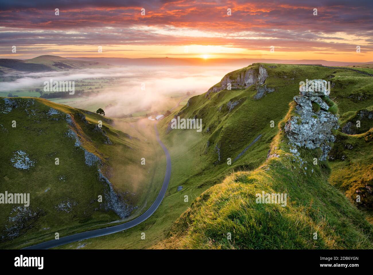 Lange kurvenreiche Landstraße, die in das neblige Tal im English Peak District führt. Stockfoto