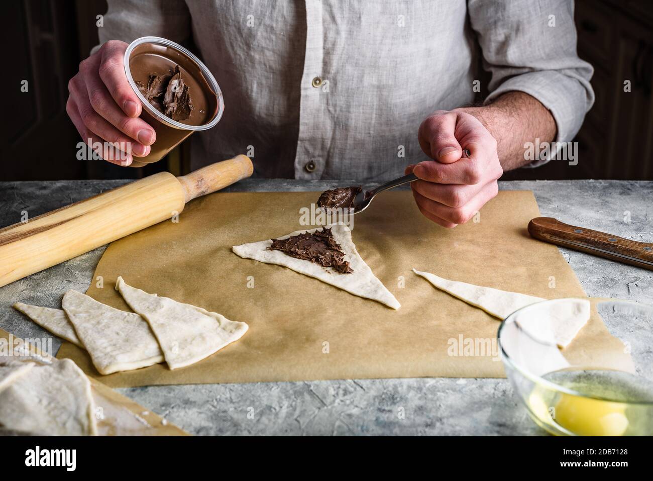 Baker verteilt Haselnuss verteilt zwischen Blätterteig Dreiecke Stockfoto