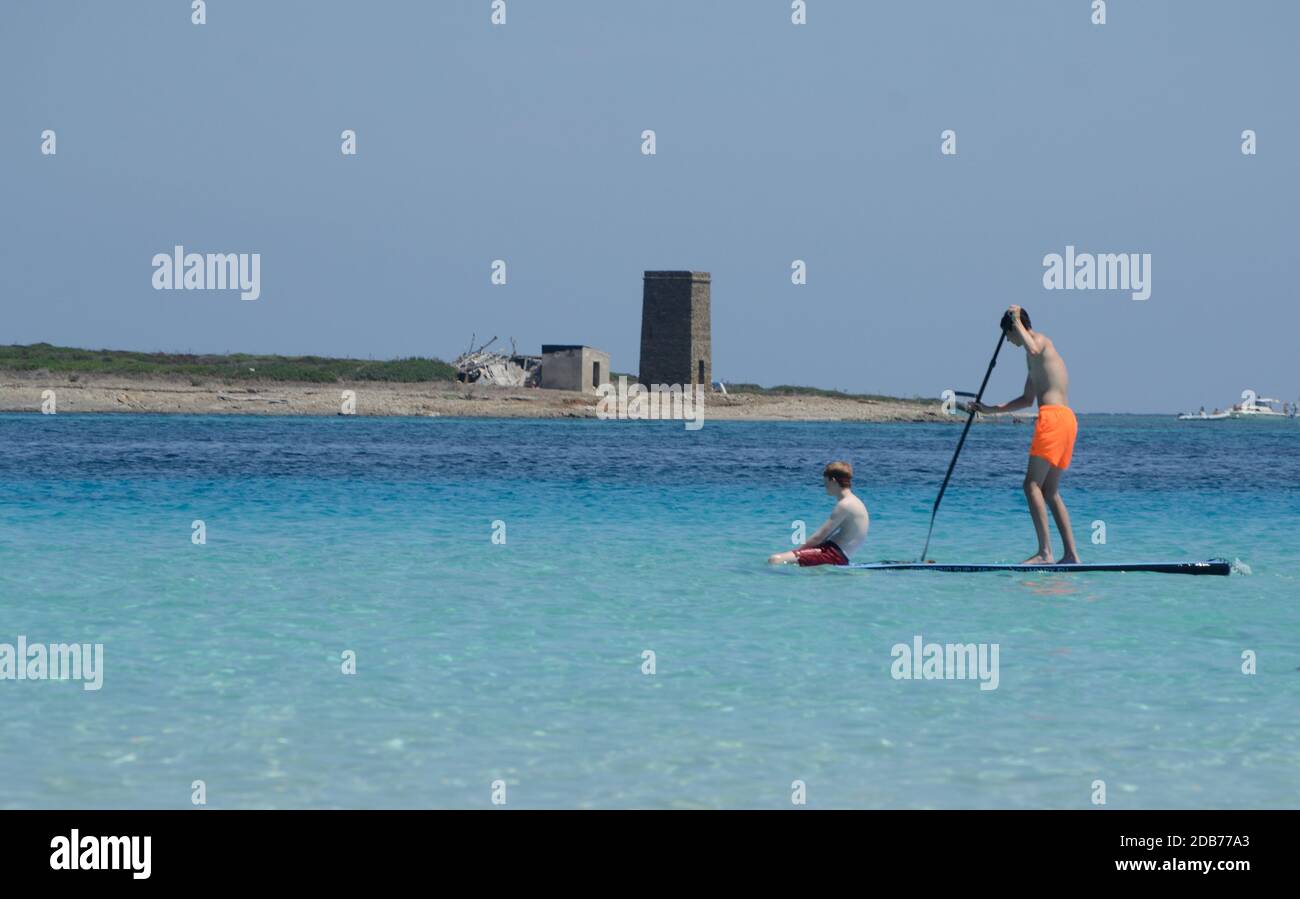 Zwei Freunde schwimmen auf Stand Up Paddle Board im türkisfarbenen Wasser vor dem La Pelosa Strand. .Wassersport, aktiver Lebensstil Stockfoto