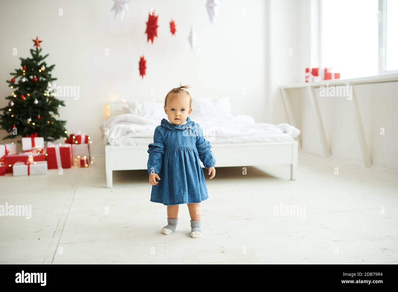 Porträt eines kleinen Mädchen in einem blauen Denim-Kleid in einem hellen Raum gekleidet. Stockfoto