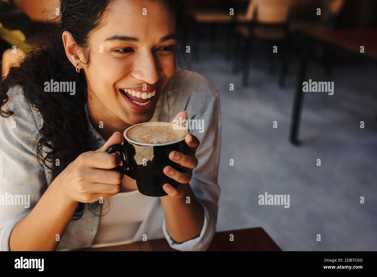 Frau mit einer Tasse Kaffee im Café sitzen. Nahaufnahme einer afrikanischen Frau mit Kaffee und Lächeln. Stockfoto