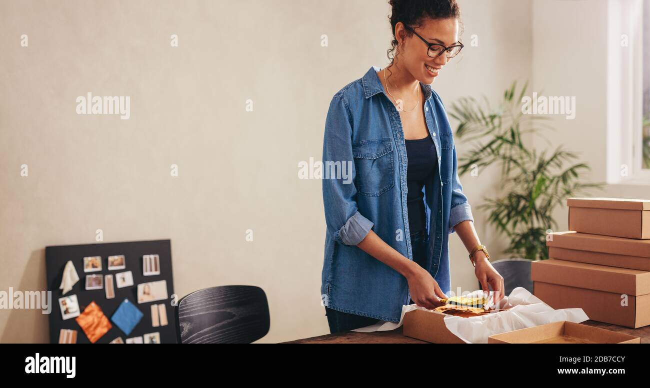 Drop Versand Unternehmer Verpackung Gesichtsmasken für Online-Lieferung an den Kunden. Frau, die im Heimbüro einen Lieferkarton verpackt. Stockfoto