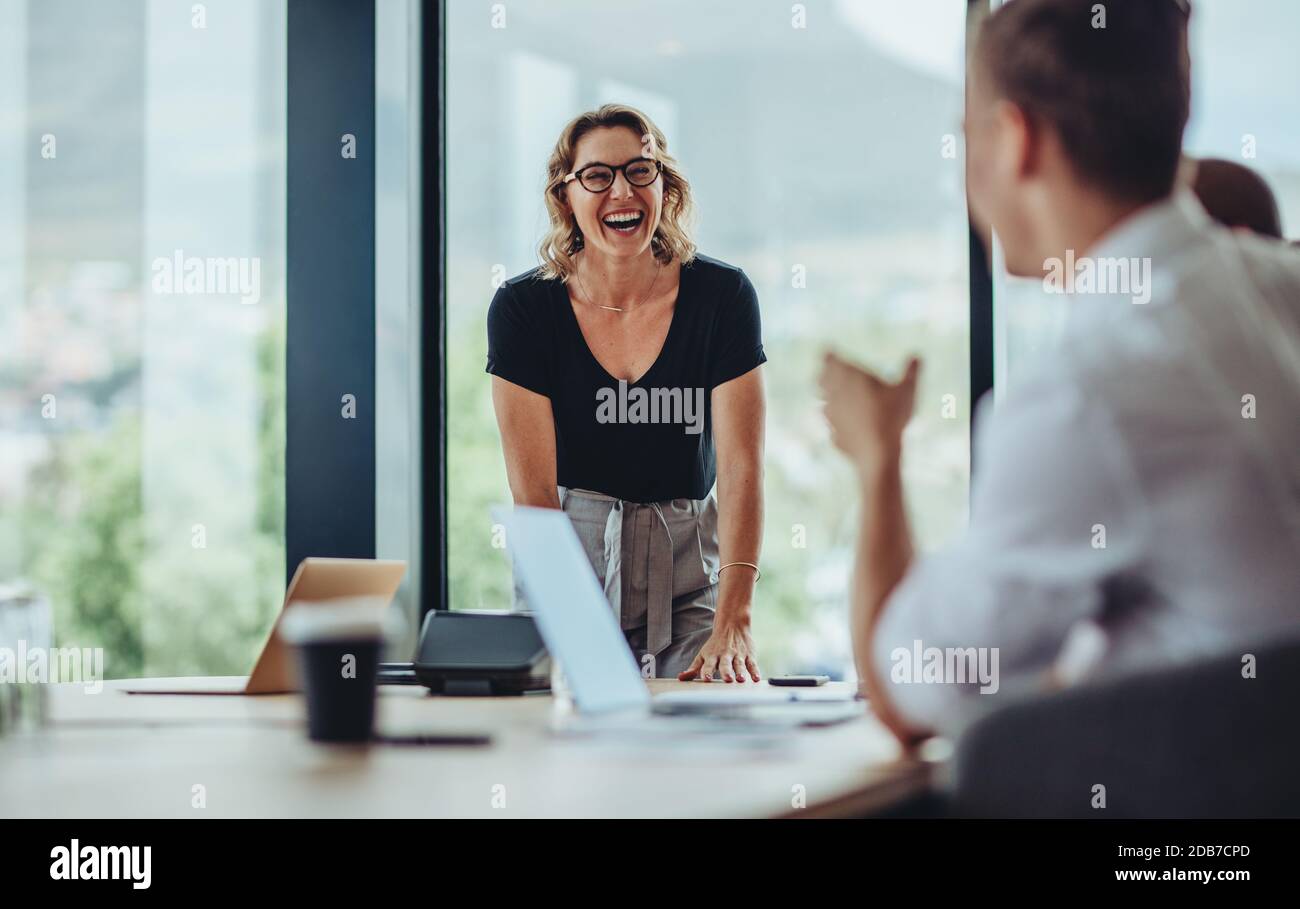 Geschäftsfrau steht am Konferenztisch und lacht. Frau lächelt während einer Besprechung im Sitzungssaal des Büros. Stockfoto