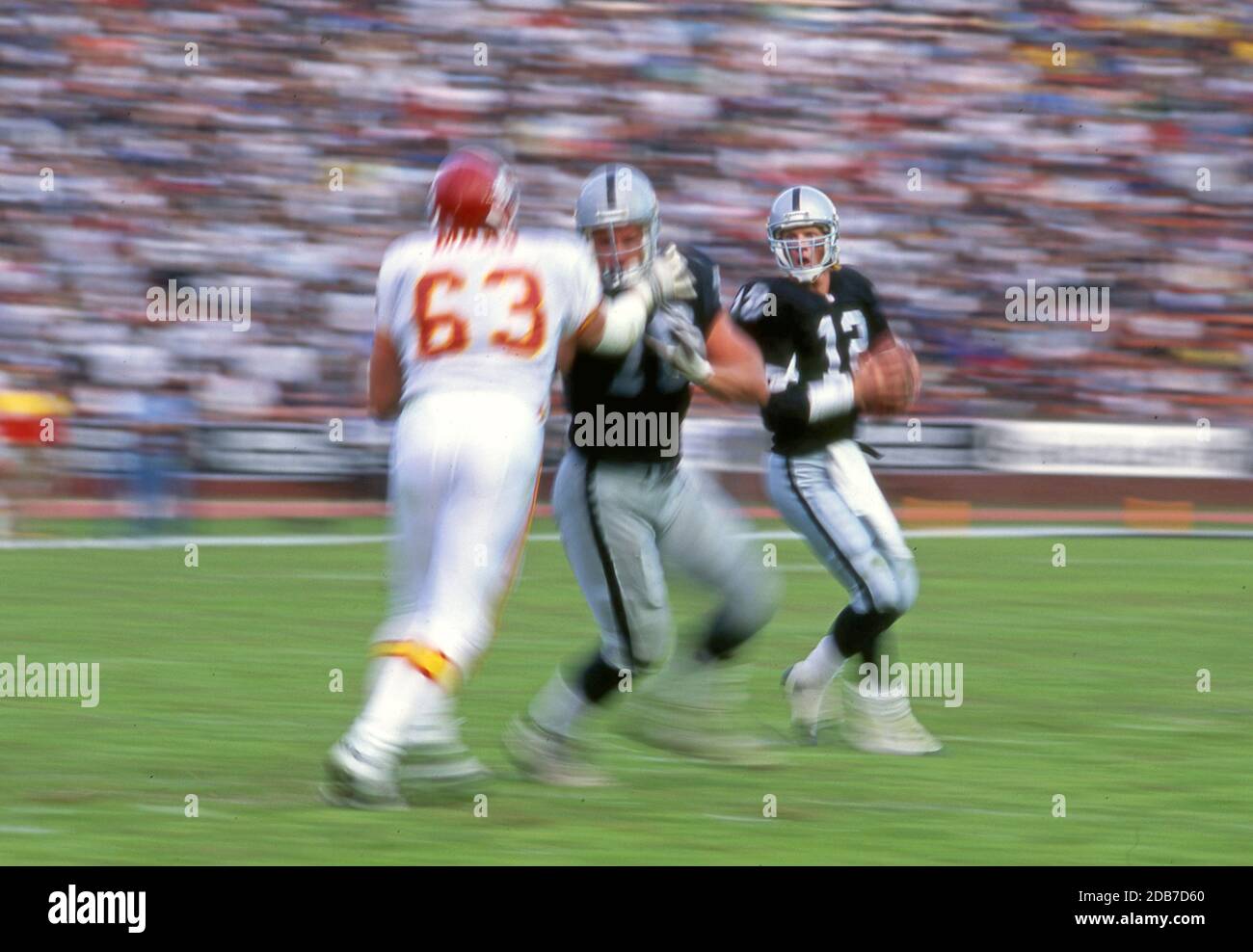 Action von NFL Football-Spiel mit Motion Blur Technik gefangen wie ein Lineman blockiert einen stürzenden Verteidiger, um den Quarterback zu schützen. Stockfoto
