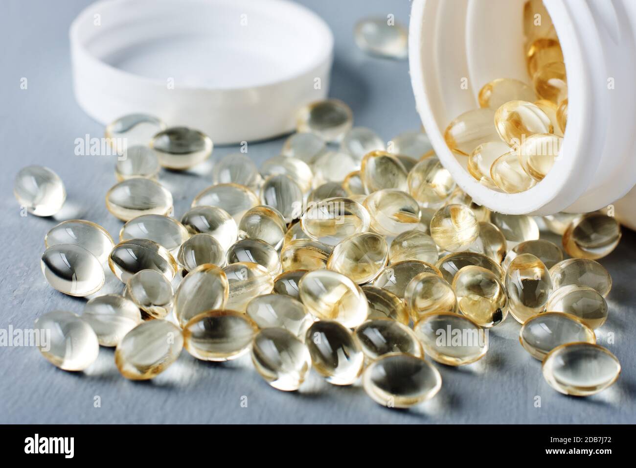 Gelbe Kapseln von Vitamin D auf einer grauen Oberfläche. Stockfoto
