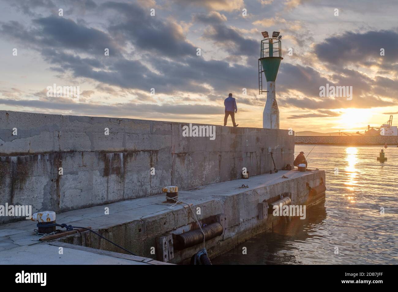Mann auf dem Pier bei Sonnenuntergang, Hafen von Burgas, Bulgarien Stockfoto