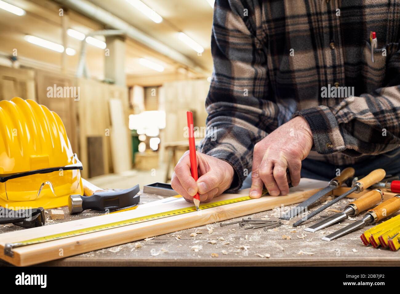 Nahaufnahme. Tischler mit Bleistift und Messgerät markiert die Messung auf einem Holzbrett. Bauindustrie, Zimmerei. Stockfoto