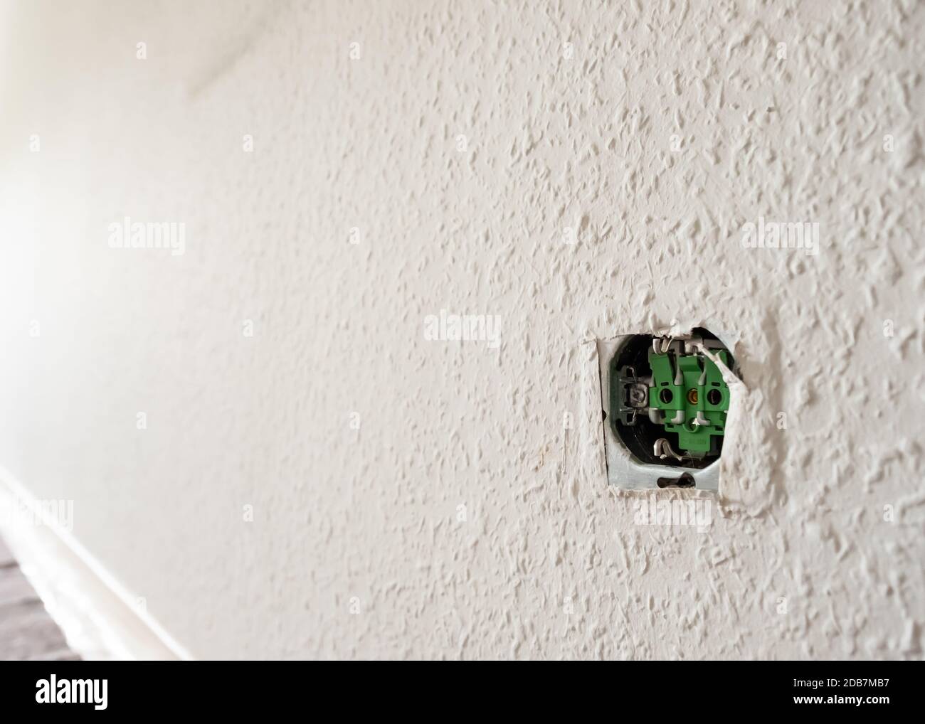 Offene Steckdose an einer Wand mit Holzschnitzeltapete im hinteren beleuchtet Stockfoto