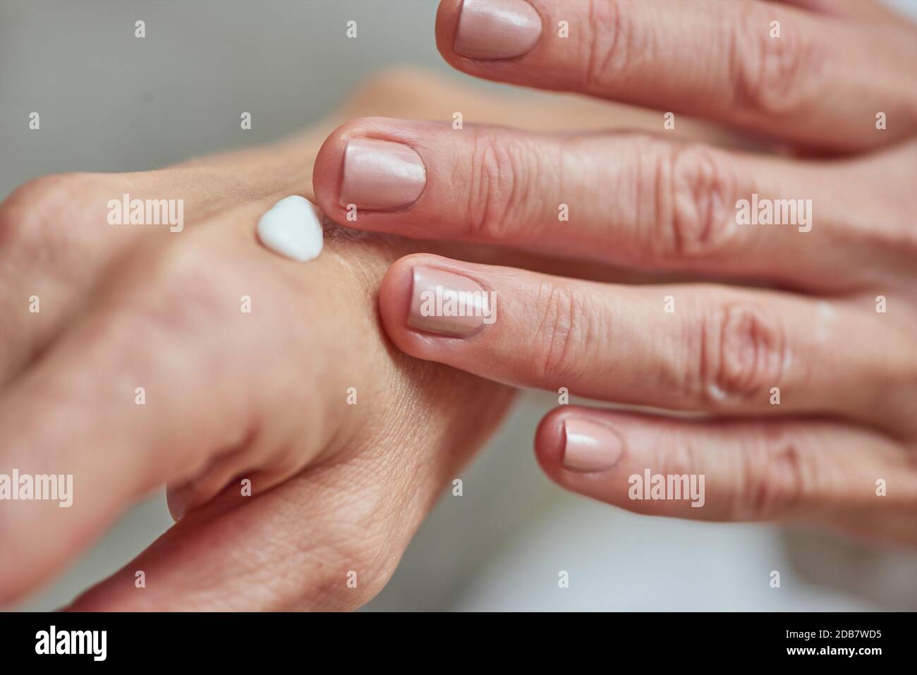 Gepflegte Hände der Frau mittleren Alters, die weiße Creme aufsetzt, Nahaufnahme. Beauty, Hautpflege und Kosmetologie Konzept Stockfoto