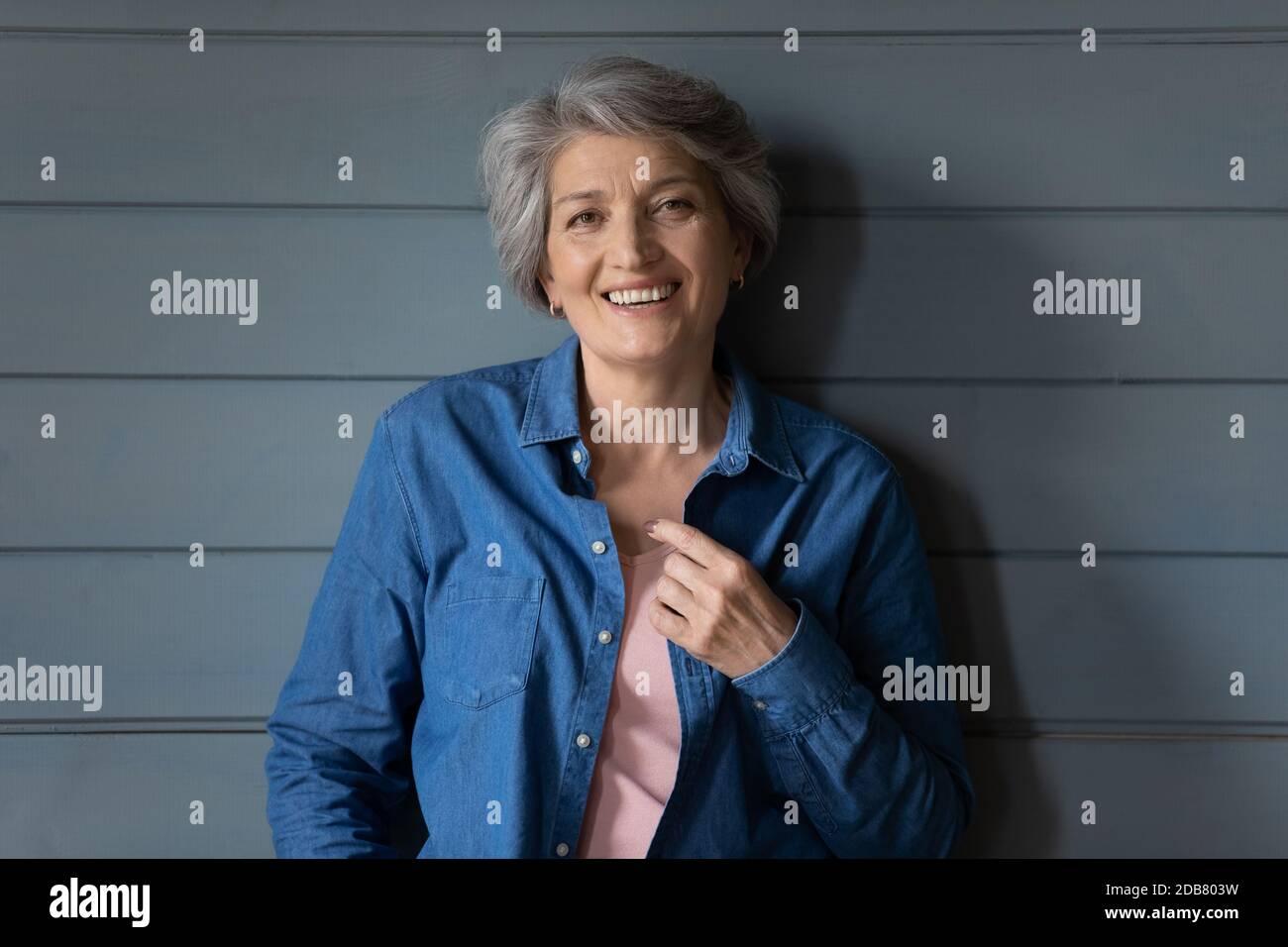 Kopf erschossen Porträt lächelnd reife Frau auf grauem Holzhintergrund Stockfoto